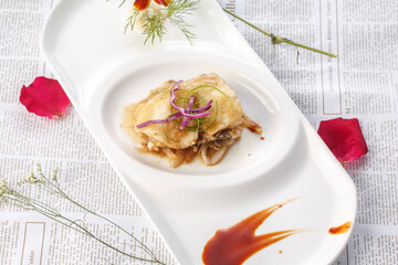 Pan-fried large conch slices with XO sauce on a white porcelain plate