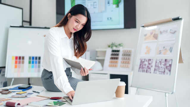 Asian Architect Woman Designs Project Details with Laptop and Material Samples Interior Design Presentation at Workplace Desk Creates Layout - Powered by Adobe