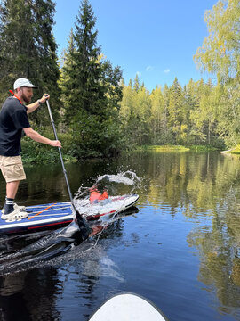 Man splashes water while paddling on forest river