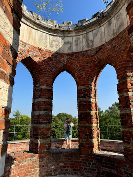 Woman standing inside old brick tower with arches