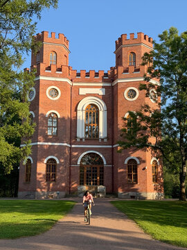 Young woman cycling in front of red brick castle