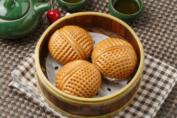 Hong Kong-style cream pineapple buns in a steamer are placed on the tablecloth