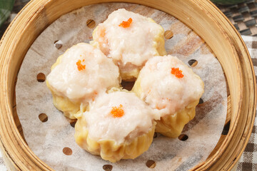 Cantonese prawn dumplings in a steamer are placed on a tablecloth