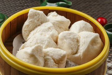 A rectangular white porcelain plate of rice rolls with shrimp is placed on a placemat