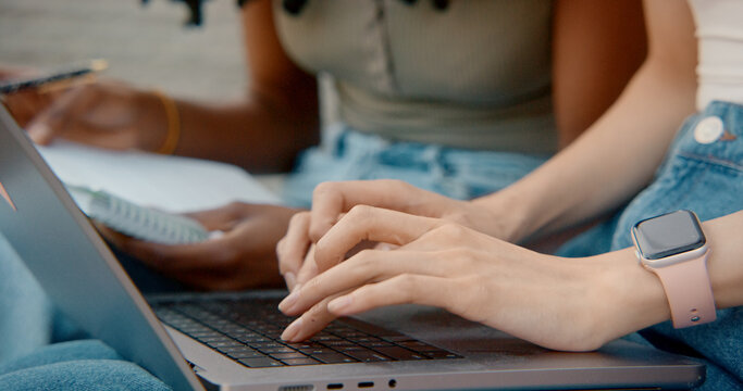 Students working on laptop and taking notes outdoors