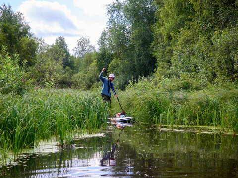 Supboard paddler pushes through dense wetland grass