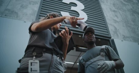 Female Coordinator Scanning Parcel with Scanner, Using Digital Tablet. Diverse Employees Carrying Cardboard Boxes to Logistics Warehouse. Online Orders, E-Commerce Goods. Low Angle Shot. Slow Motion. - Powered by Adobe