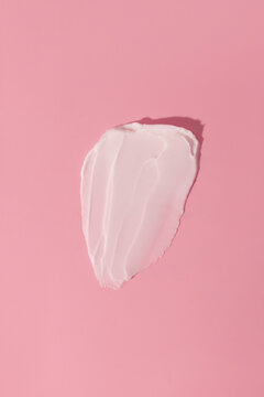 Close-up of cream smear on a pink background in minimalistic style