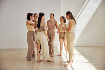 Women engaging in joyful conversation in a sunlit studio space
