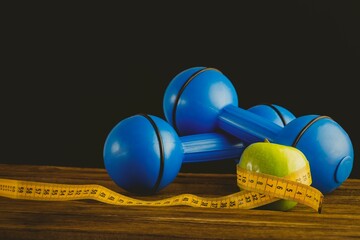 Blue dumbbells with green apple and measuring tape