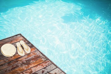 Obraz premium Hat and flip-flop on pier by swimming pool