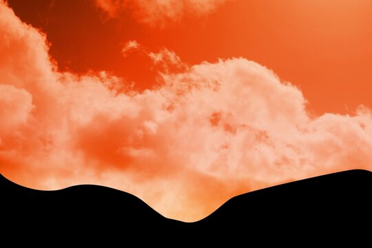 Fototapeta Vibrant red-orange sky is featuring cloud formation over smooth black hill silhouette, flat design