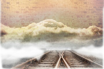 Train tracks leading to brick wall with clouds