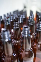 Selbstklebende Fototapeten Beer bottles arranged in row at factory © vectorfusionart