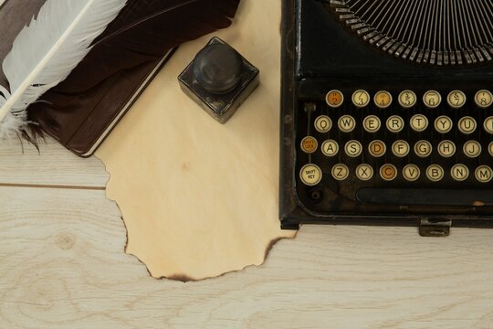 Typewriter, feather and stamp on table