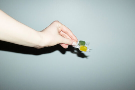 Hand holding colourful wrapped sugar sweet candy with flashlight