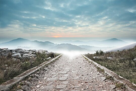 Fototapeta Stony path leading to misty mountain range