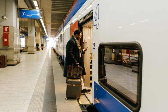 Businessman Boarding Train at Modern Station With Luggage
