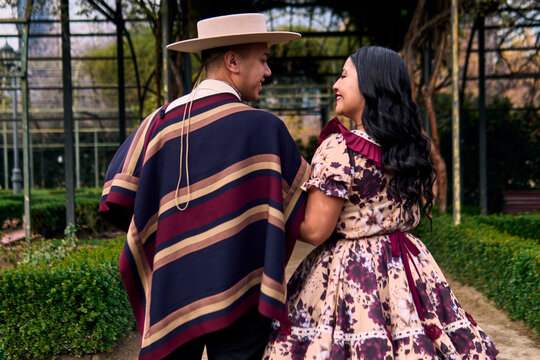 A couple of young Chilean Latin cuecas dancers, walking romantically back to back, gazing affectionately at each other. Chilean Independence Day celebration.
