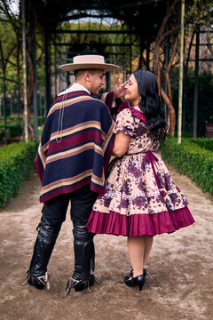 A couple of young Chilean Latin cuecas dancers, walking romantically back to back, gazing affectionately at each other. Chilean Independence Day celebration.