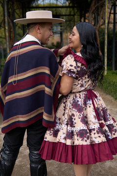 A couple of young Chilean Latin cuecas dancers, walking romantically back to back, gazing affectionately at each other. Chilean Independence Day celebration.
