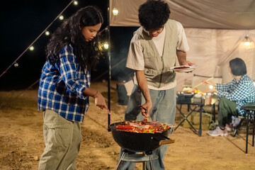 A man and a woman are cooking food on a grill. A third person is sitting at a table