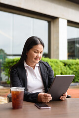 Business woman working with digital tablet computer outdoors while having iced coffee