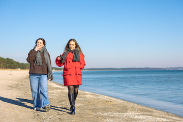 Two women walking on the seashore. Two friends enjoying and spending time together.