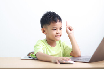 Young boy studying and doing homework at home with notebook and laptop. Concept of distance learning, education, homeschooling, and online classes for children.