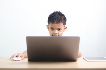 Young boy studying and doing homework at home with notebook and laptop. Concept of distance learning, education, homeschooling, and online classes for children.