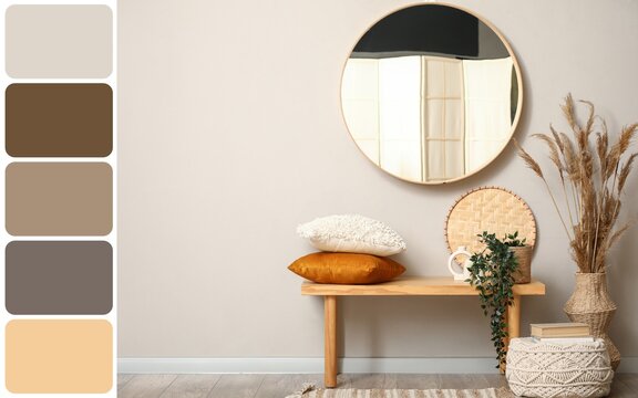 Bench with pillows and mirror on grey wall in interior of room. Different color patterns