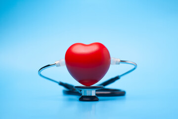 Red heart shape exercise ball with doctor physician's stethoscope on blue background, hospital life insurance concept, world heart health day. doctor day