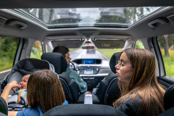 Kids on the road. Baby crying in car seat. Real family moment.