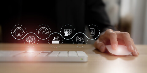 Digital wellbeing in workplace concept. Using a computer mouse, overlaid with icons representing digital wellbeing,  healthy work-life balance. Promoting a healthy relationship with technology.