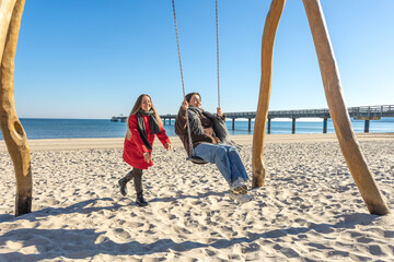 Two women swinging on a swing on the beach. Sea. Beach. Vacation with a friend.