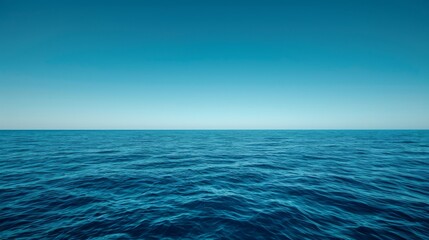 Fototapeta premium Serene ocean waves gently lapping against a deep blue surface beneath a clear sky