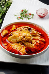 Spicy chicken in a white porcelain bowl on a fan-shaped porcelain plate