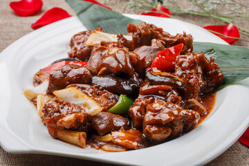 Braised pork knuckle and trotter with mushrooms in a white round porcelain plate