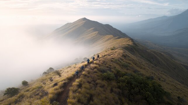 drone view of hikers trekking mountain ridge trail with backpacks at sunrise