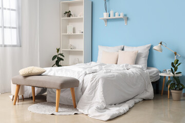 Interior of cozy bedroom with comfortable bed and grey bench