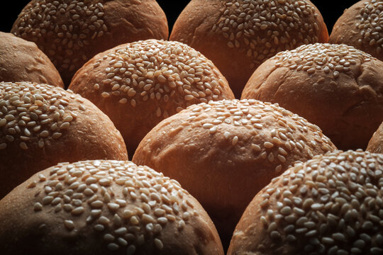 many baked sesame topping burger breads lay on oven tray waiting for cooking, shot with shallow focusing and tilted lens effect for background wallpaper