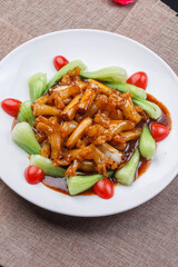 Braised sea cucumber tendons with scallions on a white round porcelain plate