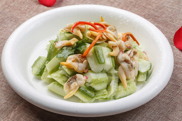 Stir-fried melon with clam meat in a white round porcelain plate
