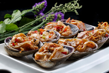 Seafood charcoal grilled purple stone clam swan eggs in a tripod-shaped porcelain plate