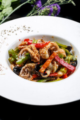 Octopus fried with seafood sauce in a white round porcelain plate