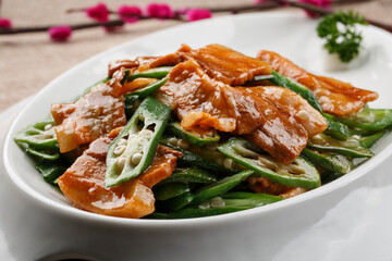 Fried pork belly with fresh okra served in white porcelain tableware