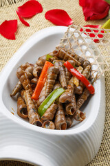 Spicy fried giant screw snails in a white porcelain plate
