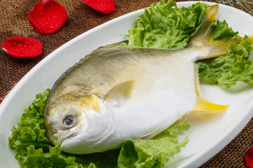 Fresh golden fish in a white oval porcelain plate