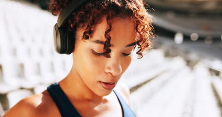 Breathing, exercise and music with woman outdoor in stadium for break, recovery or rest from...