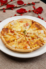 Homemade corn and ham pizza on a white porcelain plate